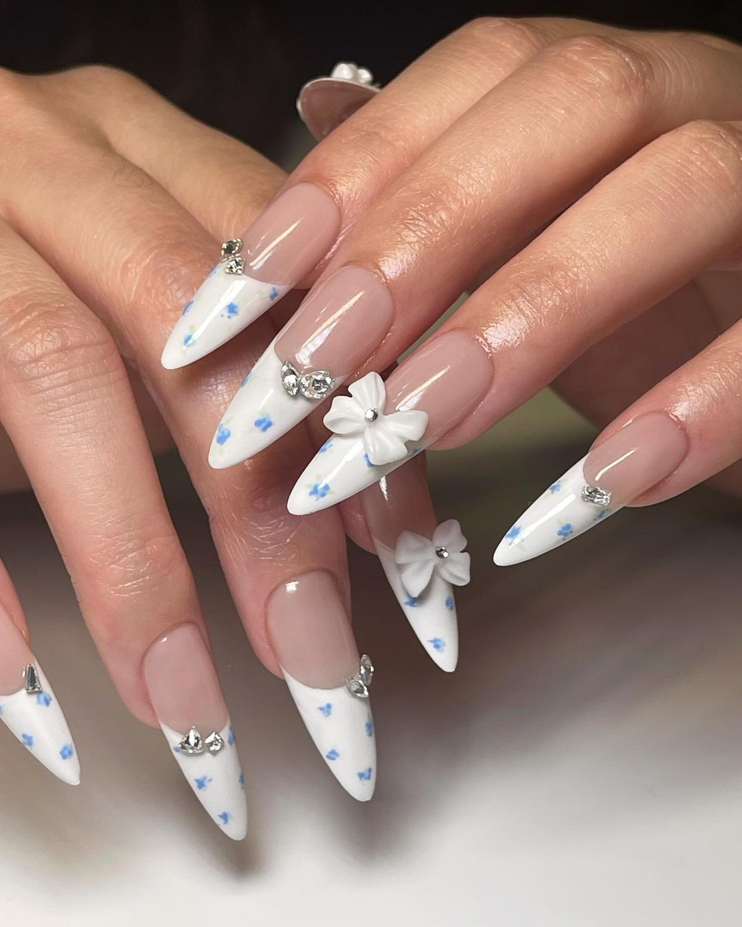 White Stiletto Nails with Blue Flower Prints and 3D Bow Embellishments