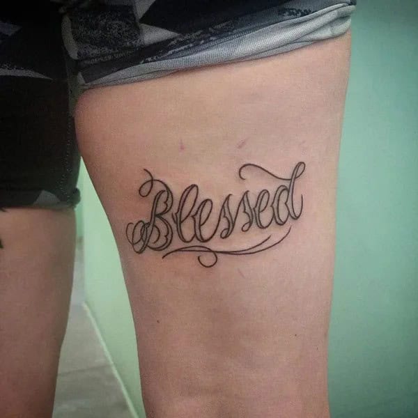 Blessed tattoo on thigh